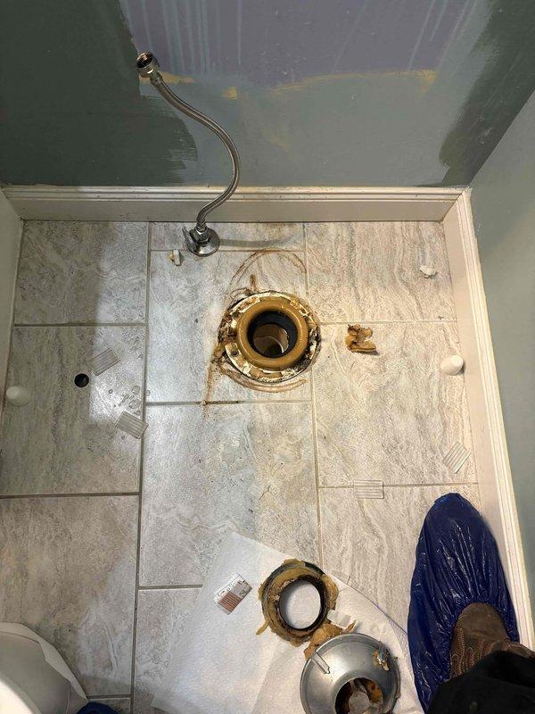 Responded to a leaking toilet. Removed the toilet from the flange, inspected the flange and surrounding tile, and removed the failed wax ring, which was coated in residue and the source of the leak. Cleaned the flange and floor area, then reset the toilet on a new wax ring and reconnected the braided supply line to the angle stop to restore a watertight seal.