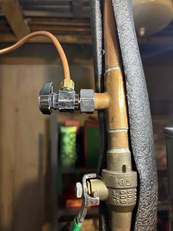 Inspected the humidifier supply line from the water heater and located the leak at the chrome angle stop valve and compression connection, which showed tarnishing, residue, and discoloration consistent with a slow weep. Isolated the water supply using the in-line 3/4" brass ball valve, serviced the angle stop and compression fitting feeding the Aprilaire humidifier's copper supply tube, and restored water service. Verified no remaining leaks at the tee, valve, or tubing connections.