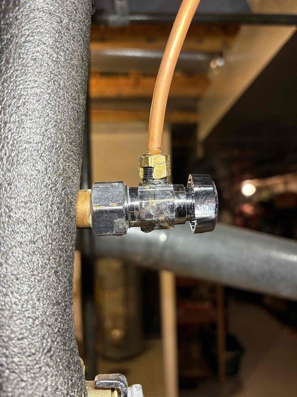 Inspected the humidifier supply line from the water heater and located the leak at the chrome angle stop valve and compression connection, which showed tarnishing, residue, and discoloration consistent with a slow weep. Isolated the water supply using the in-line 3/4" brass ball valve, serviced the angle stop and compression fitting feeding the Aprilaire humidifier's copper supply tube, and restored water service. Verified no remaining leaks at the tee, valve, or tubing connections.