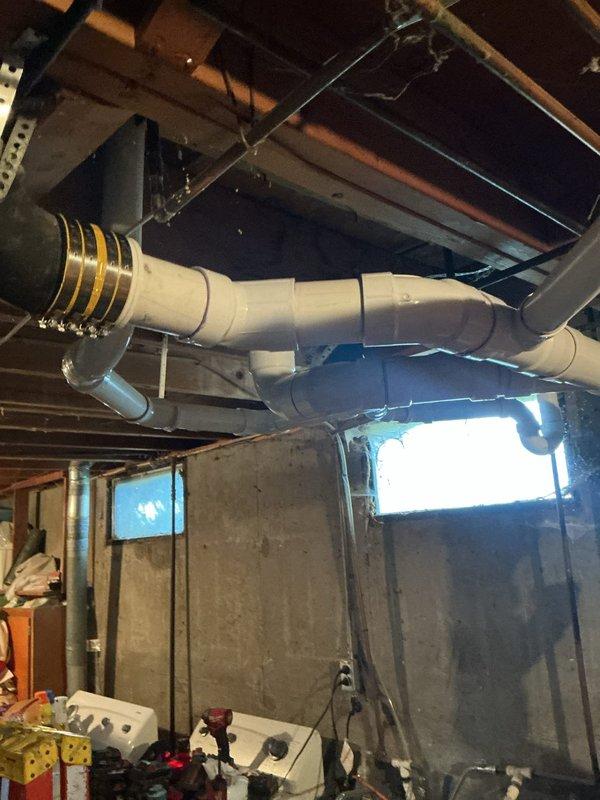 Repiped the basement drain line using new white PVC with fitted elbows, couplings, and a wye, and connected it to the existing galvanized drain with a secured rubber transition coupling and band clamps. Installed a pump-in-a-box system, routing the discharge through the foundation wall, and completed the work over a 1.5-day period.