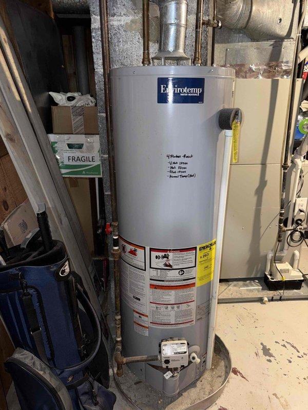 Inspected a 9-year-old gas tank water heater with no hot water due to an extinguished pilot light and a non-functioning relight mechanism. Evaluated the gas control valve assembly, pilot system, and flue connection for the cause of the pilot failure and ignition fault. The unit is installed in a drain pan with a vented flue in the basement utility space and was documented with photos of the tank, labels, and surrounding piping.