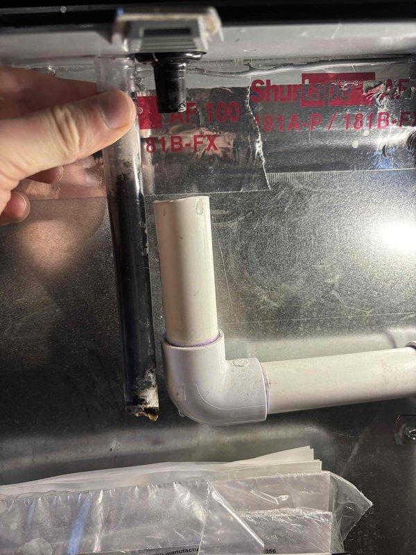Inspected the Goodman furnace and associated condensate drain system to diagnose the reported water leak. Found the condensate drain tubing at the PVC drain connection partially obstructed with debris and buildup, causing water to back up and overflow. Cleared the clogged drain tubing, verified proper flow through the PVC drain line and elbow, and confirmed secure hose clamp and fittings with no further leakage observed.