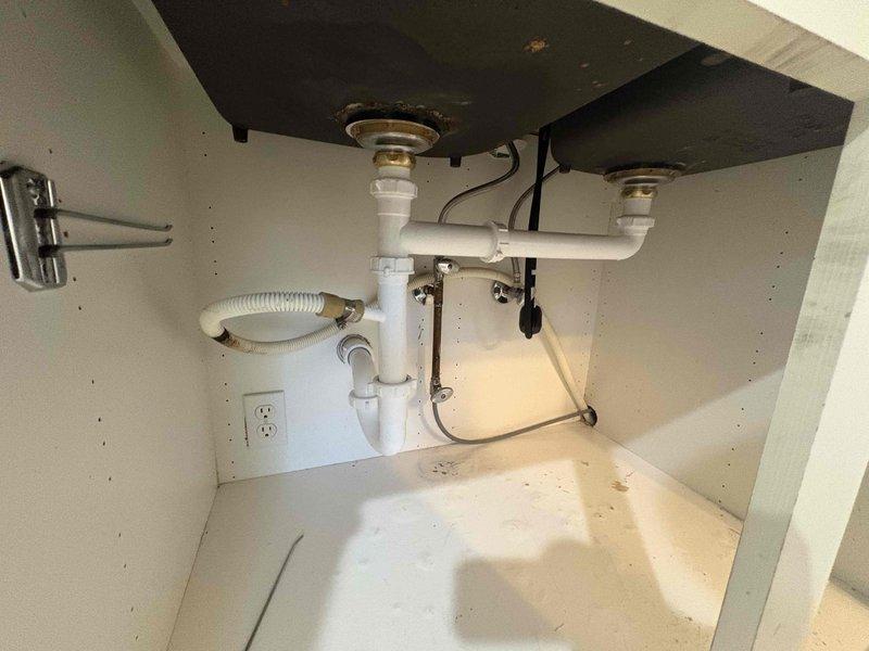 Removed the existing kitchen faucet and garbage disposal from the double-basin sink and installed the customer-supplied brushed stainless pull-down faucet with matching soap dispenser. Reconnected the angle stop valves and supply lines, restored the drain assembly with the dishwasher drain line, and verified proper operation with no leaks.