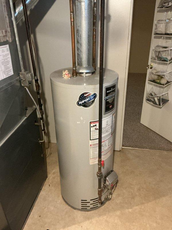 Performed on-site estimate for replacement of a 12+ year-old atmospheric-vent gas tank-type water heater in a single-family home. Inspected the existing unit, galvanized flue/vent connection, gas supply with flexible connector and control valve, and copper supply piping; no active leaks, corrosion, or damage observed on the tank, though surface rust was noted on adjacent black iron piping. Documented the installation with photos and reviewed replacement options with the customer.