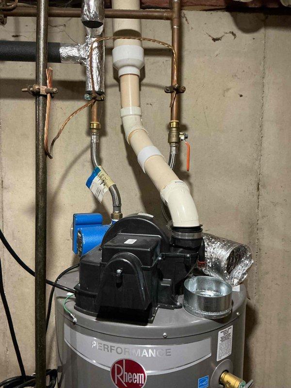 Assessed a leaking standard tank-type, natural gas Rheem Performance power-vent water heater manufactured January 2021, with evidence of moisture at the base of the tank, and documented the existing power-vent assembly, PVC venting, flexible water connectors, shutoff valve, and surrounding copper piping. Findings support full unit replacement, and the estimate was prepared for a like-for-like power-vent tank replacement.