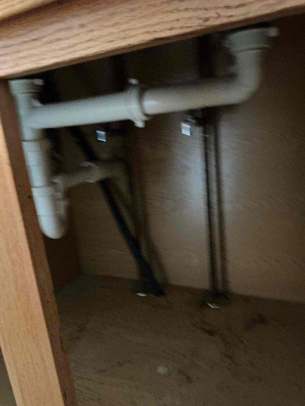 Inspected a 30-year-old drop-in sink with a backed-up drain and found the sink's drain bottom to be rotted, which is the cause of the blockage. Examined the under-sink PVC drain assembly, including the P-trap, slip-nut couplings, and supply lines, and documented their condition with photos. Advised that the sink will require either drain repair or full sink replacement to restore proper drainage.