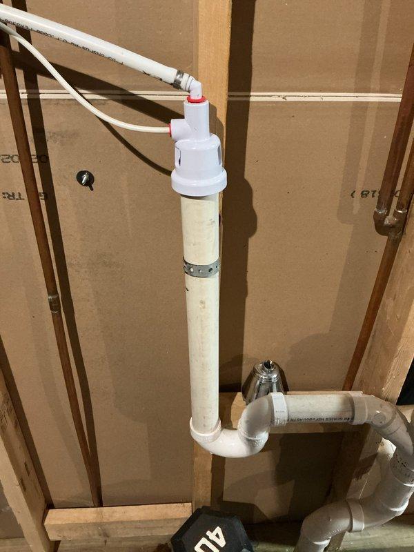 Installed a special-order dual-port air gap on the dishwasher and appliance drain line, connecting both flexible drain hoses and securing the vertical PVC standpipe with a band clamp to the existing P-trap and horizontal drain run. Verified all connections were secure and the assembly was clean and dry, with no leaks observed.