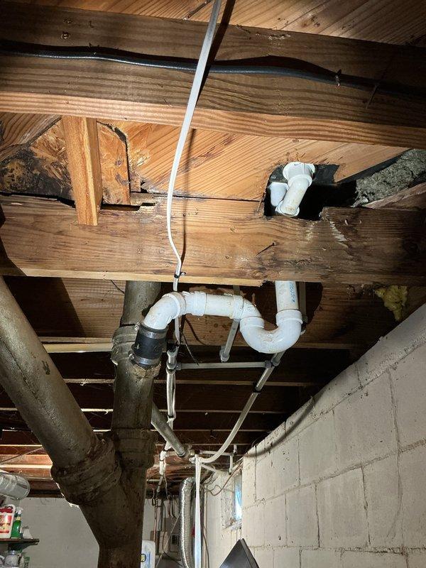 Evaluated a sewage leak at the basement level and inspected the bathroom drain, waste, and vent assembly, including the cast iron stack, PVC P-trap, and rubber coupling connections, and found aged, corroded cast iron with water-damaged, deteriorated subfloor and joists beneath the bathroom. Assessed the wall cavity behind the toilet and vanity and the upper drain stack transition between floors for additional leak sources, with access approved to remove drywall and shiplap as needed. Scoped the scope of a bathroom remodel and associated drain repairs, and flagged the affected area for electrical and mold evaluation.