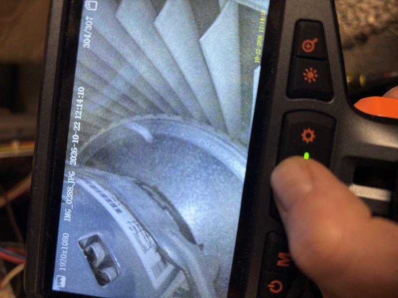 Performed a comprehensive tune-up on a 14-year-old Heil gas furnace, including a borescope inspection of the blower assembly and motor housing, which showed dust and debris accumulation on the blower wheel and interior surfaces. The inspection also revealed heavy scale and corrosion buildup with flaking along the rim and walls of a circular opening in the heat exchanger or flue passage, which should be monitored given the age of the unit. Completed the standard tune-up and verified the furnace is operating safely.