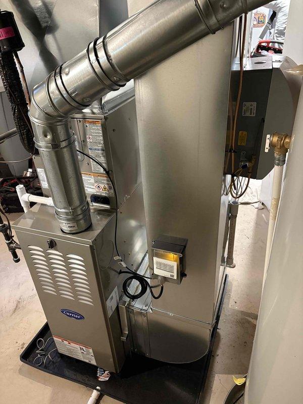 Installed a new Carrier gas furnace with a vented flue assembly, sheet-metal supply plenum, and condensate drain pan, along with an accessory air treatment component, and completed the associated gas, electrical, and drain connections. Installed a matching Carrier outdoor condensing unit on a level concrete pad with insulated refrigerant lines and a weatherproof electrical disconnect, completing the full furnace/AC system replacement.