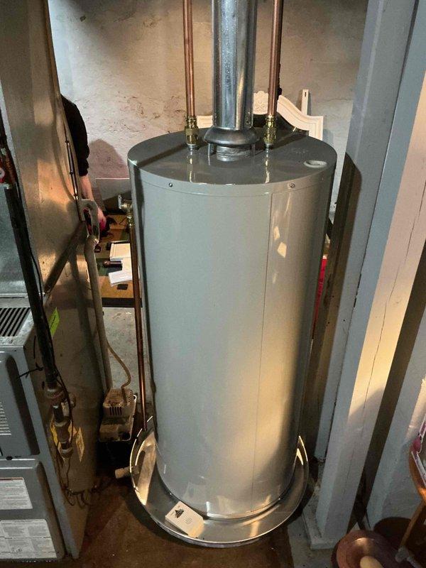 Removed the existing unit and installed a new 40-gallon natural gas, non-direct-vent Bradford White water heater, set in a drain pan and connected to the existing galvanized flue/vent piping. Reconnected the hot and cold copper supply lines with shutoff valves and the gas line, then verified the installation was secure and the unit was ready for operation.