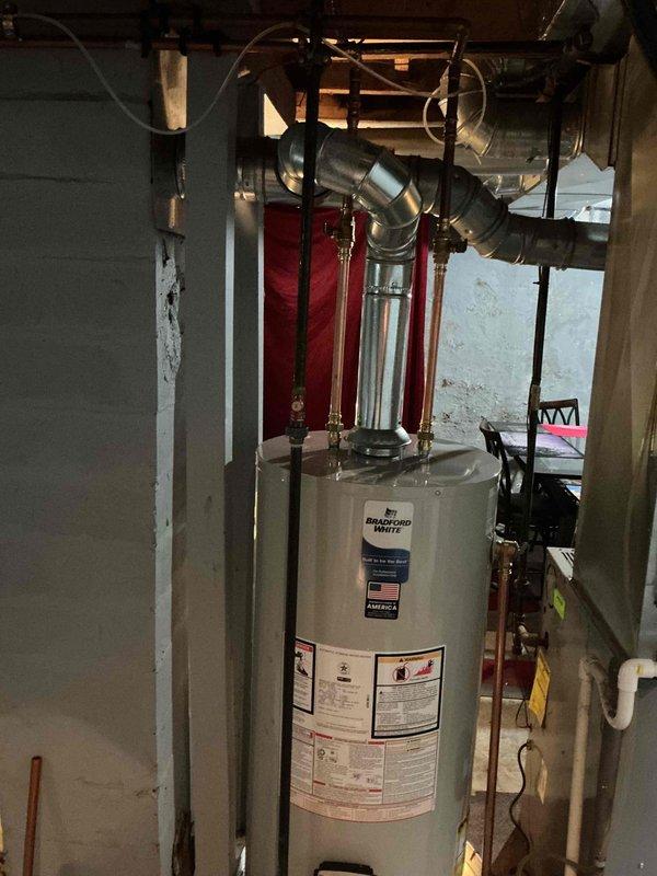 Removed the existing unit and installed a new 40-gallon natural gas, non-direct-vent Bradford White water heater, set in a drain pan and connected to the existing galvanized flue/vent piping. Reconnected the hot and cold copper supply lines with shutoff valves and the gas line, then verified the installation was secure and the unit was ready for operation.