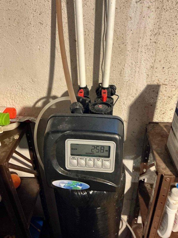 Responded to a water softener leak caused by a component that detached from the bypass valve assembly while the customer attempted to isolate the unit. Inspected the softener, control head, and associated plumbing connections, confirmed the water supply was shut off, and addressed the failed bypass fitting to stop the leak. Documented the unit's condition and surrounding moisture with photos.