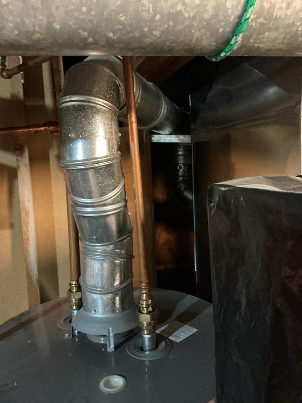 Responded to a reported leak at a gas-fired Rheem water heater and inspected the unit, including the flue connection, supply piping, and base of the tank. Found water pooling at the base with containment buckets and absorbent towels already in place, and no visible corrosion or damage on the top fittings, copper supply lines, or flue assembly. Documented the unit's condition with photos and recommended further evaluation of the tank and relief valve discharge line to pinpoint the leak source and determine whether repair or replacement is required.