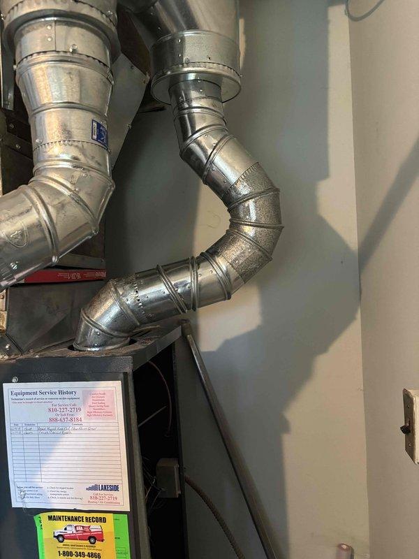 Inspected the water heater flue and vent piping installed above the furnace and found the segmented galvanized exhaust routing obstructed access to the HVAC filter. Adjusted and realigned the vent piping and draft hood connection to restore clearance for filter removal and replacement, and verified the vent connections were secure with the equipment operating properly.