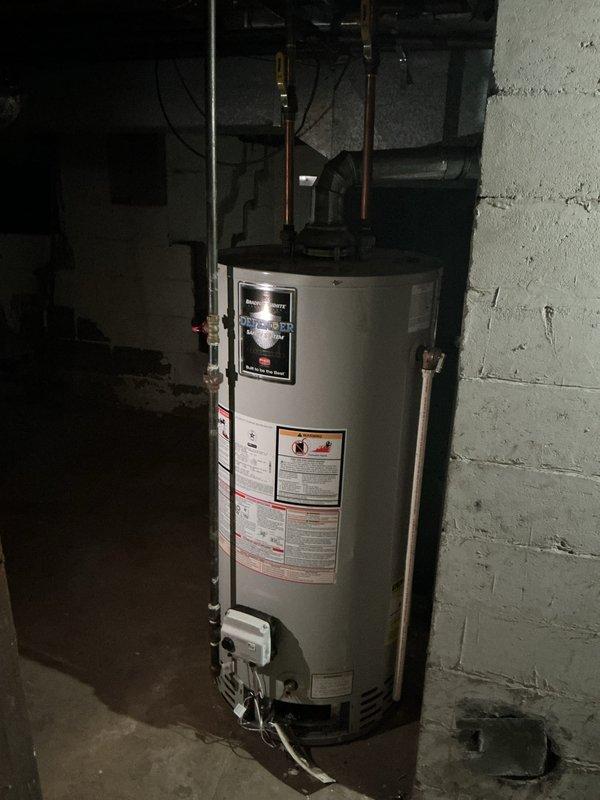 Inspected a 40-gallon Bradford White natural gas tank water heater (approx. 7 years old) for a pilot that would not stay lit and a yellow burner flame. Evaluation found noticeable rust and corrosion at the flue collar and lower vent connector, indicating compromised venting and likely contributing to poor combustion and flame instability. Recommended addressing the corroded vent components and performing burner/pilot assembly service to restore proper blue-flame operation and safe draft.