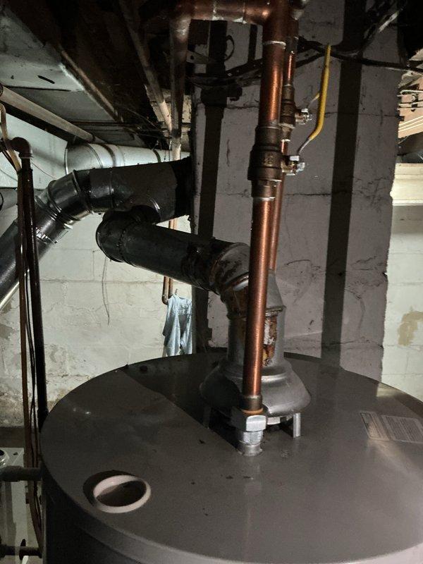 Inspected a 40-gallon Bradford White natural gas tank water heater (approx. 7 years old) for a pilot that would not stay lit and a yellow burner flame. Evaluation found noticeable rust and corrosion at the flue collar and lower vent connector, indicating compromised venting and likely contributing to poor combustion and flame instability. Recommended addressing the corroded vent components and performing burner/pilot assembly service to restore proper blue-flame operation and safe draft.