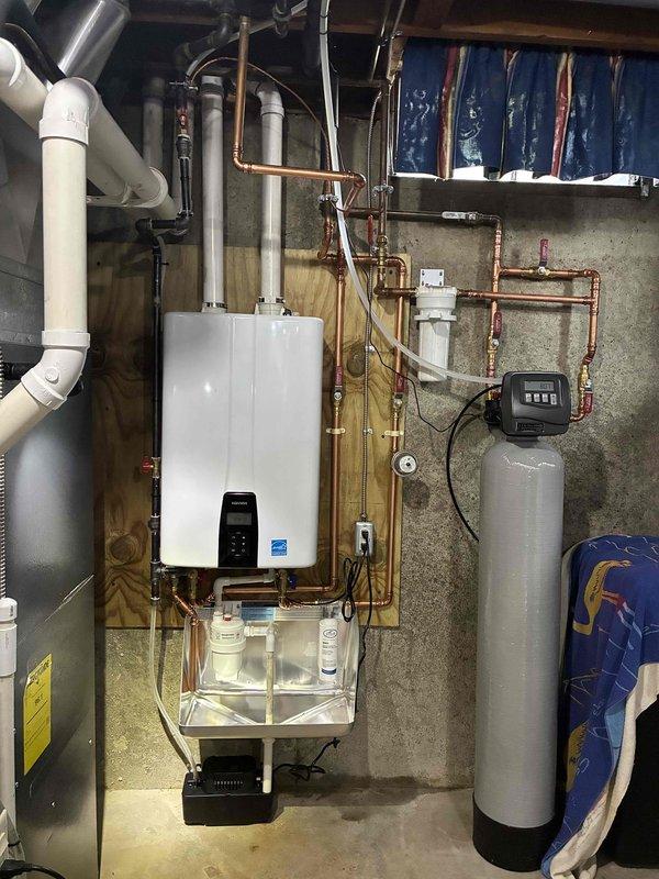 Installed a wall-mounted condensing tankless water heater on a plywood backboard, with PVC intake/exhaust venting routed to the ceiling, copper supply and return piping with soldered joints and isolation shutoff valves, and an inline sediment filter. Connected the condensate drain to a condensate pump, then verified secure connections, proper venting, and no visible leaks at completion.