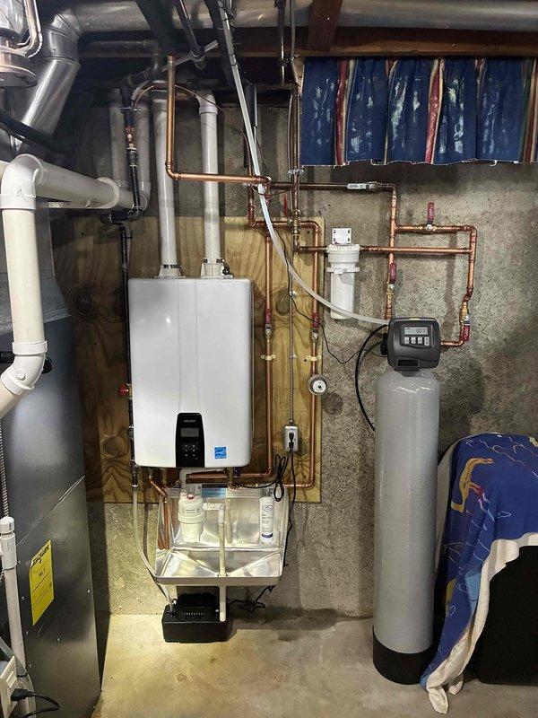 Installed a wall-mounted condensing tankless water heater on a plywood backboard, with PVC intake/exhaust venting routed to the ceiling, copper supply and return piping with soldered joints and isolation shutoff valves, and an inline sediment filter. Connected the condensate drain to a condensate pump, then verified secure connections, proper venting, and no visible leaks at completion.