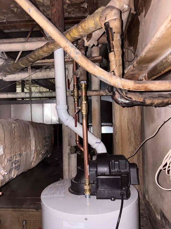 Installed a new 40-gallon power-vent natural gas water heater with a blower assembly, connecting the gas supply, water lines with isolation valves, and PVC venting routed through the roof penetration with an inverted-U termination, and wired the power supply to the blower. Verified proper gas connections, vent integrity, and operation. Noted aged, deteriorated, and heat-damaged insulation on adjacent overhead piping, along with heavily cracked roof membrane near the vent termination, both recommended for further evaluation.