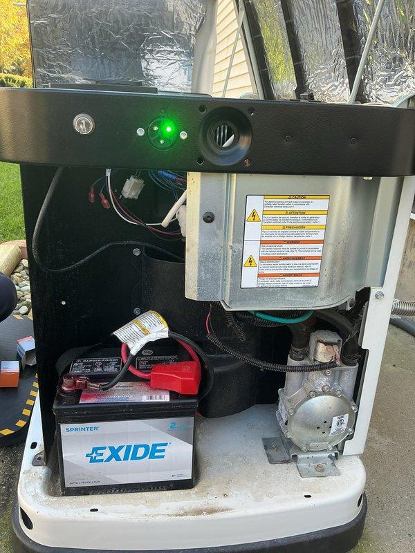 Installed an auxiliary shutoff switch for the standby generator, wiring it into the control circuit through the transfer/control enclosure and the dual-pole 60-amp breaker compartment. Terminations were secured at the brass terminal studs and insulated connectors, and the generator's control panel was verified to power up with the status indicator illuminated and the battery connected.