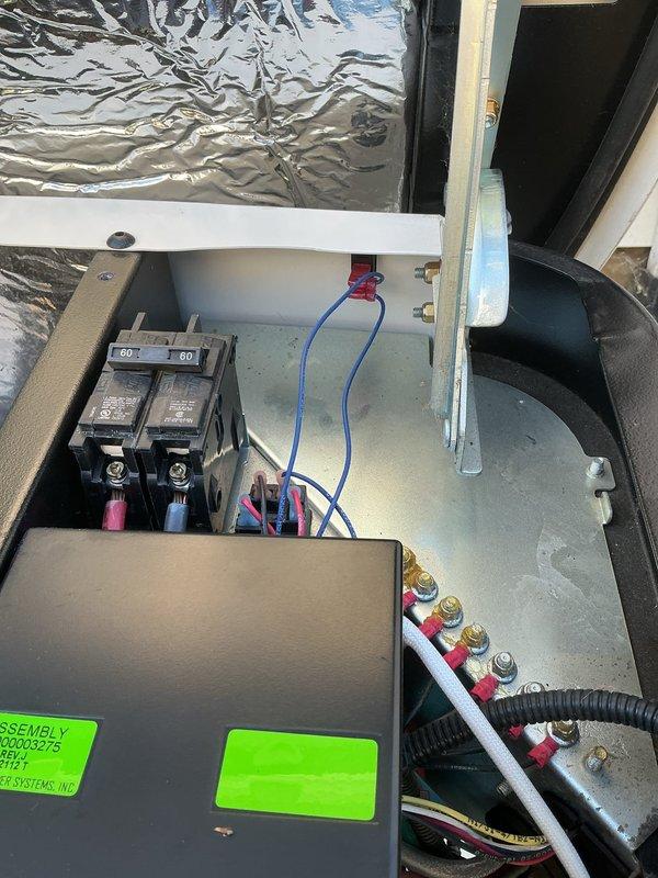 Installed an auxiliary shutoff switch for the standby generator, wiring it into the control circuit through the transfer/control enclosure and the dual-pole 60-amp breaker compartment. Terminations were secured at the brass terminal studs and insulated connectors, and the generator's control panel was verified to power up with the status indicator illuminated and the battery connected.