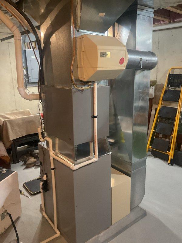 Performed a Furnace Super Tune-up on a 9-year-old Heatcraft gas furnace with an attached whole-house humidifier. Removed the upper access panel and inspected the blower motor, wiring harnesses, and control assembly, then verified proper operation of the heating system. Checked the condensate drain line and PVC venting for secure connections, and noted light rust staining on the concrete floor at the base of the furnace cabinet for monitoring.