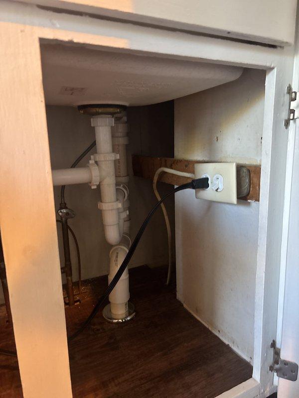 Installed the new sink and reverse osmosis system, connecting the drain assembly with a P-trap and slip-joint fittings and tying into the existing copper supply line with angle-stop valves. Verified all connections were secure and free of leaks, with the under-sink cabinet cleared and the plumbing and electrical supply left properly arranged.