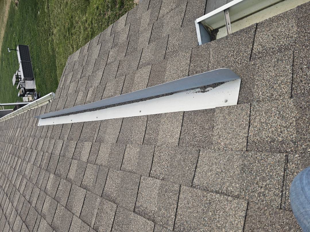 A homeowner contacted us regarding water staining on their ceiling. Upon inspection, we identified several issues. The back flashing appeared old and needed attention. The screws securing it were loose, and the flashing itself required slight adjustments to ensure a better seal. Additionally, we discovered a bird's nest obstructing the downspout, which could lead to further water damage. We proposed a solution to address these problems. First, we re-secured the loose screws and adjusted the flashing to improve its effectiveness. Next, we removed the b