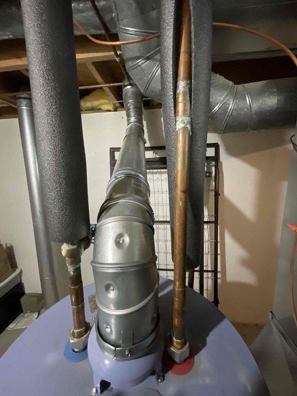 Conducted replacement estimate for 35-year-old furnace and A/C system located in basement. Current equipment is operational but at end of life expectancy. Inspection revealed confined installation space with multiple plumbing lines and ductwork requiring careful consideration for new equipment placement. Noted existing water heater with vertical exhaust system and insulated copper piping that will need to be worked around during replacement.