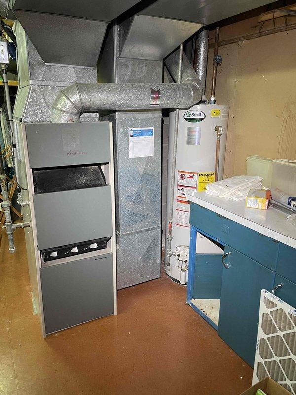 Provided quote for replacement of 30+ year old non-functional furnace and A/C system located in basement (BOGO offer). System evaluation included inspection of electrical panel with proper circuit identification and assessment of existing ductwork configuration, which consists of insulated metal ducts branching from the current Goodman unit, alongside an A.O. Smith water heater in the utility area.