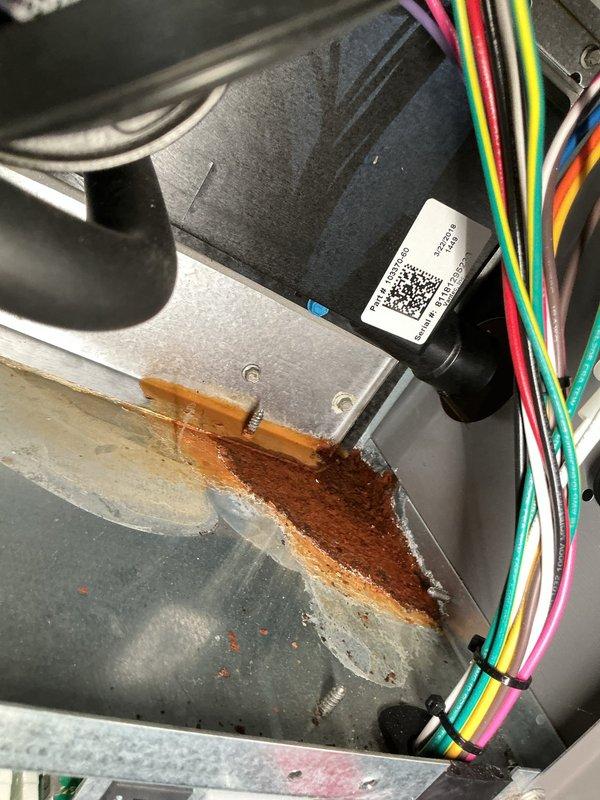 During routine maintenance, identified water leak causing significant corrosion on the interior metal housing of HVAC equipment. Performed diagnostic assessment and documented damage with photographic evidence, including rust formation on electrical components near wiring harness and verified level positioning of the unit.