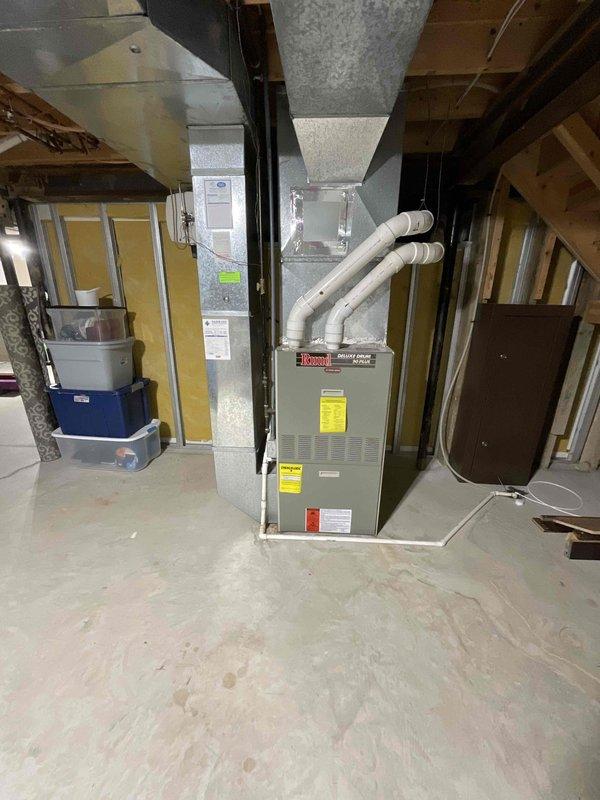 Conducted comprehensive evaluation of aging HVAC system (25-year-old natural gas furnace and AC unit) for potential replacement. Inspected basement-installed furnace with PVC exhaust venting and connected ductwork, along with outdoor AC condenser unit (protected by lattice enclosure) showing signs of age-related wear. System currently operational but approaching end of service life; replacement options presented to improve efficiency and reliability.