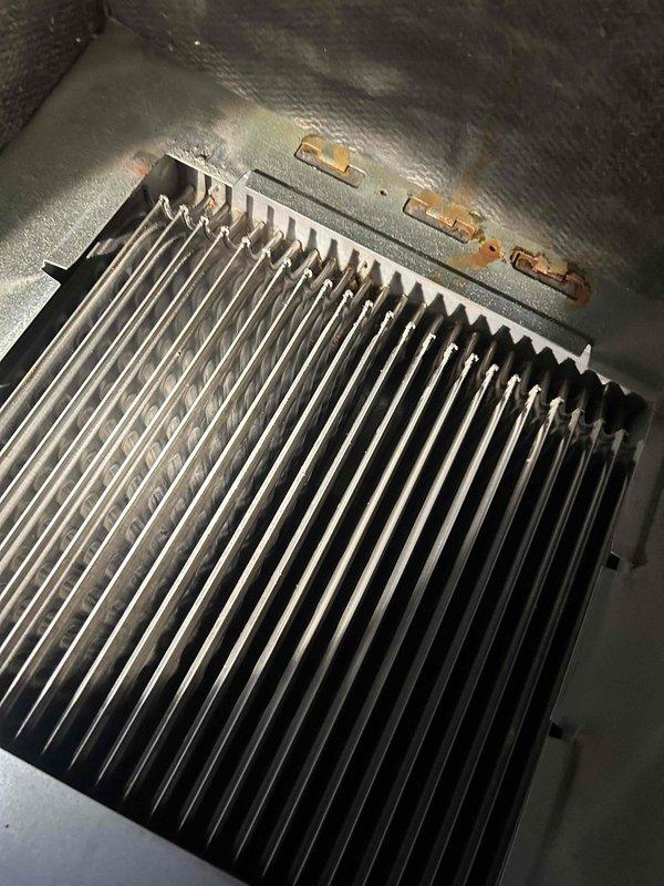 Responded to no-heat call for forced air system. Inspected heat exchanger and cooling coils, finding significant corrosion and rust formation on metal housing and base of fins. Cleaned accumulated dust/debris from between cooling fins to restore proper heat transfer and system operation.