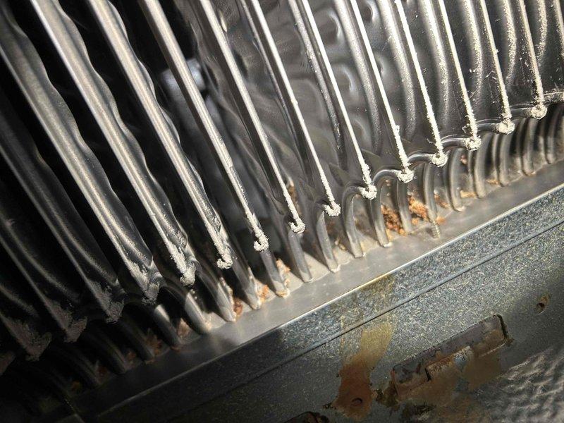 Responded to no-heat call for forced air system. Inspected heat exchanger and cooling coils, finding significant corrosion and rust formation on metal housing and base of fins. Cleaned accumulated dust/debris from between cooling fins to restore proper heat transfer and system operation.