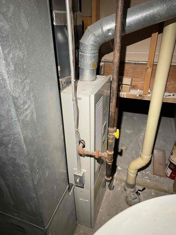 Performed assessment of aging furnace and A/C system in basement for replacement estimate. Current equipment is operational but significantly outdated. Inspection revealed existing ductwork configuration with galvanized metal transitions and exposed utilities, including electrical wiring and plumbing lines running through floor joists, which will need to be considered during replacement planning.
