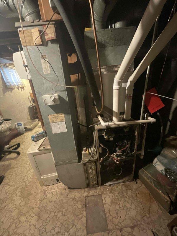 Conducted assessment of non-operational 15-year-old natural gas furnace in basement mechanical room. Inspection revealed electrical component failure requiring complete system replacement. Documented current installation configuration including ductwork connections and proximity to water heater for proper replacement unit specifications.