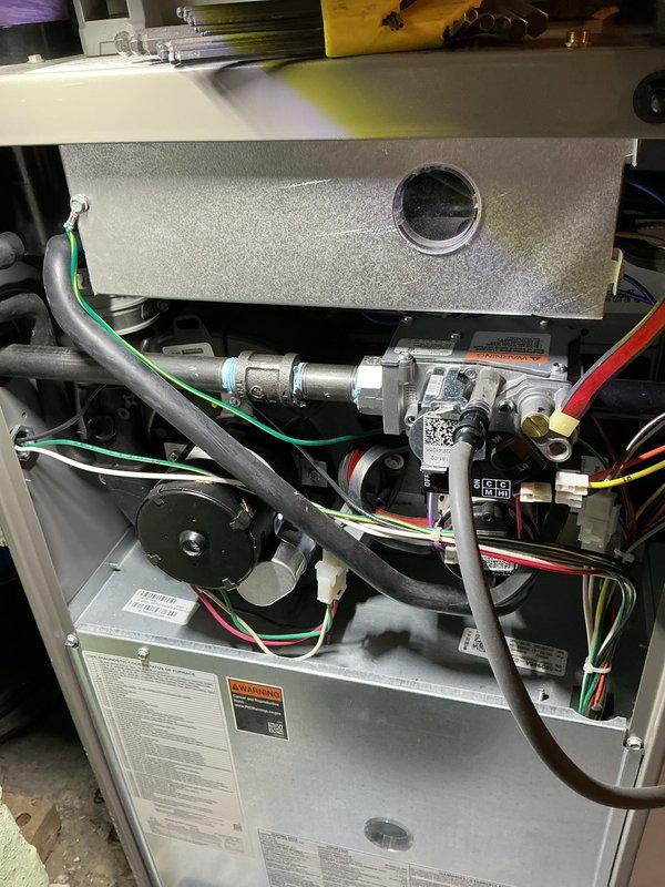 Completed annual heating maintenance on customer's furnace under Air Care membership. Inspected gas valve assembly and associated electrical connections, finding all components in proper working order. Noted wall deterioration around vent pipe penetration with exposed insulation that should be sealed to prevent further damage and maintain system efficiency.