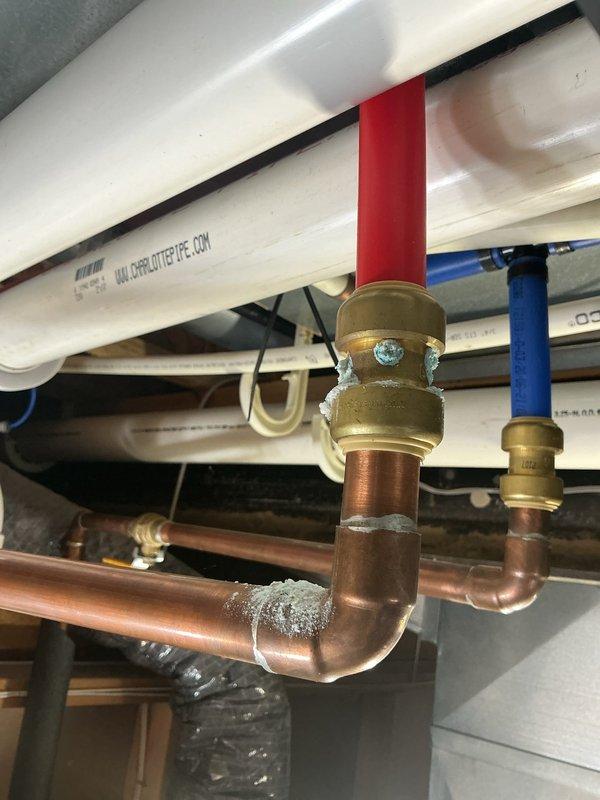 Diagnosed warranty-covered tankless water heater installed in 2022 that exhibited leakage and calcium buildup. Inspection revealed significant corrosion and mineral deposits at copper pipe joints connecting to the unit, particularly at brass fittings where advanced oxidation had formed. Cleaned affected components and replaced damaged copper pipe section to resolve the leak.