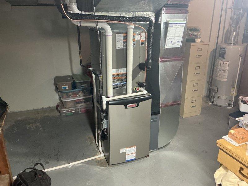 # HVAC Install - Complete System

## Summary
Successfully completed full HVAC system replacement including installation of 110,000 BTU furnace and 4-ton air conditioning unit with left-side configuration, humidifier integration, and reconnection of all existing utilities.

## Work Performed

Removed existing HVAC equipment and installed new Lennox furnace system with 110,000 BTU heating capacity in basement mechanical room. Mounted furnace cabinet on concrete floor with proper clearances and secured unit to manufacturer specifications.

Installed 4-ton air conditioning system with left-side refrigerant line configuration to match existing infrastructure. Connected air handler plenum to furnace discharge and secured all ductwork connections with appropriate sealing methods. Installed silver-insulated rectangular plenum above furnace unit and connected black flexible ductwork for proper air distribution.

Integrated humidifier system into new furnace installation, connecting water supply