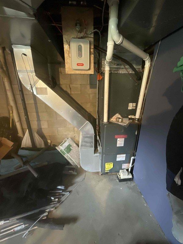 Conducted on-site evaluation for complete HVAC system replacement. Assessed existing 16-year-old furnace and air conditioning units located in basement mechanical room. Documented current equipment configuration including dark-colored furnace unit, existing PVC venting system, ductwork layout, and electrical connections. Photographed installation area showing concrete block walls, available clearances, and current piping arrangements to facilitate accurate equipment sizing and replacement planning for spring installation.