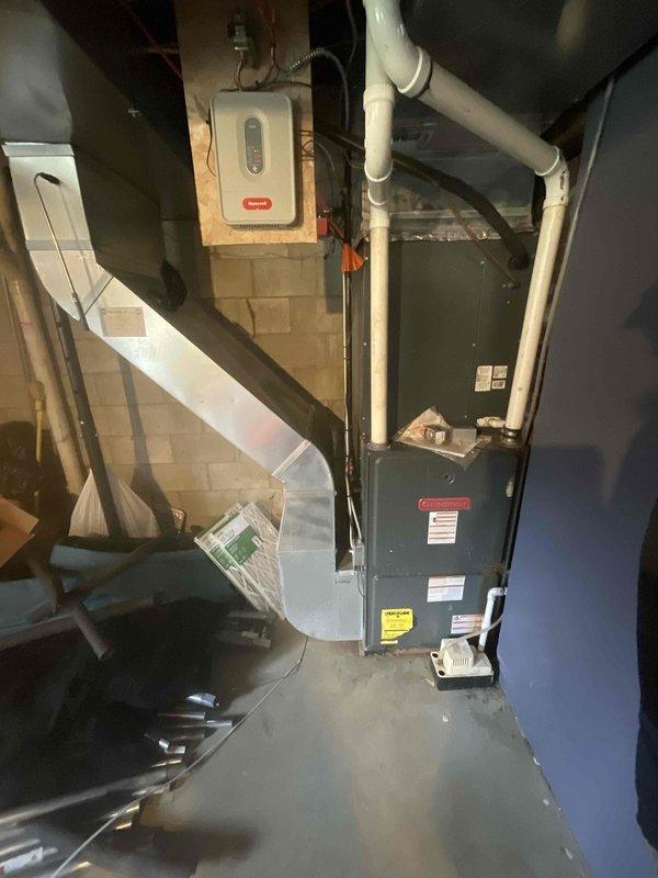 Conducted on-site evaluation for complete HVAC system replacement. Assessed existing 16-year-old furnace and air conditioning units located in basement mechanical room. Documented current equipment configuration including dark-colored furnace unit, existing PVC venting system, ductwork layout, and electrical connections. Photographed installation area showing concrete block walls, available clearances, and current piping arrangements to facilitate accurate equipment sizing and replacement planning for spring installation.