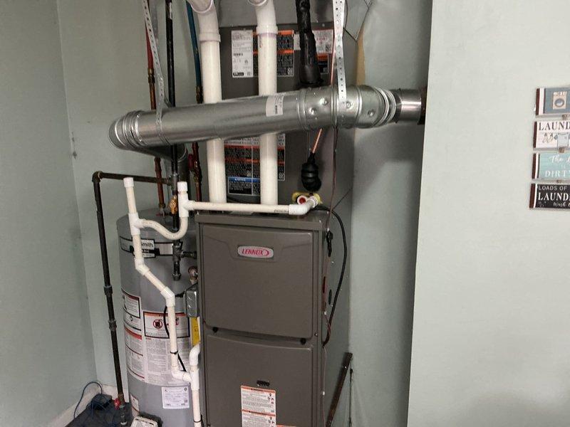 Completed full HVAC system installation including a 70,000 BTU Lennox furnace and 2.5 ton air conditioning unit with rear discharge configuration. Installed new metallic ductwork with elbow joints and support brackets, ran white PVC condensate drain lines from furnace to proper drainage point, and connected copper refrigerant lines between indoor and outdoor units. Installed chimney liner for proper venting, reconnected all electrical connections to panel box, and secured black flexible conduit and wiring along mechanical infrastructure. All plumbing connections, including water heater integration, were completed per code requirements. System tested and verified operational upon completion.