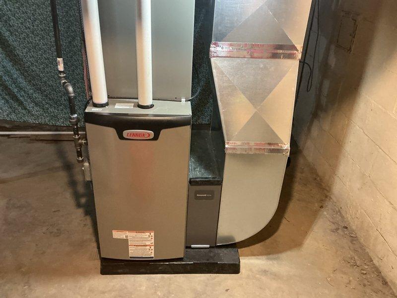 Completed full HVAC system installation including Lennox 70,000 BTU furnace and 2.5 ton air conditioning unit with rear discharge configuration. Installed furnace on platform in basement utility area with proper clearances, ran white PVC intake and exhaust venting vertically from unit, and connected refrigerant lines along wall with appropriate insulation. Fabricated and installed sheet metal ductwork with reinforced connections extending from furnace to distribution points throughout structure. Reconnected humidifier to new system and completed all electrical connections. Secured necessary mechanical permits prior to installation and documented completed work with photographs showing proper equipment placement, vent terminations, and ductwork routing.