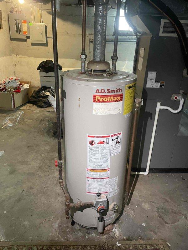 Provided estimate for replacement of existing A.O. Smith ProMax standard natural draft water heater due to venting and drafting issues identified during previous furnace service. Assessed current installation location, clearances, and chimney venting system in basement utility area. Estimate includes new standard water heater installation, chimney liner replacement, and new chimney cap to resolve improper draft conditions affecting current unit operation.