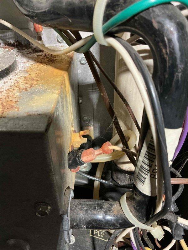 Responded to service call for communication issues between thermostat and furnace located in basement. Upon inspection, found significant rust and corrosion on furnace cabinet and internal components, indicating age-related deterioration. Examined control board wiring connections and traced communication failure to compromised wire connections affected by moisture exposure and cabinet corrosion. Documented equipment condition showing extensive oxidation on metal housing, deteriorated cabinet base where unit meets concrete pad, and multiple wire splices with aging connectors. Recommended system evaluation due to advanced corrosion affecting electrical components and cabinet integrity, which poses reliability concerns for continued operation.