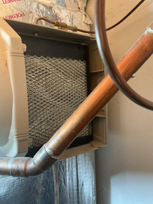 Completed routine ACM preventive maintenance on residential HVAC system. Inspected air handler unit in attic space, verified thermostat operation on Honeywell digital control and Healthy Climate accessory unit, and documented system condition with copper refrigerant lines showing age-appropriate patina but maintaining integrity. All components functioning within normal parameters with filter and controls operating properly.