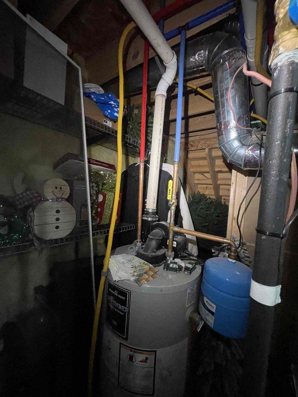 Conducted on-site assessment for replacement estimate of 13-year-old forced air furnace and air conditioning system. Evaluated existing HVAC equipment located in utility space, documented current installation configuration including ductwork routing, venting arrangements, and electrical connections. Photographed mechanical room layout showing water heater proximity, available clearances for new equipment installation, and existing PVC condensate drain lines. Assessed attic/basement space constraints, noting spray foam insulation application and structural framing that will impact equipment placement and duct modifications. Provided comprehensive replacement quote for new heating and cooling system to address aging equipment concerns.