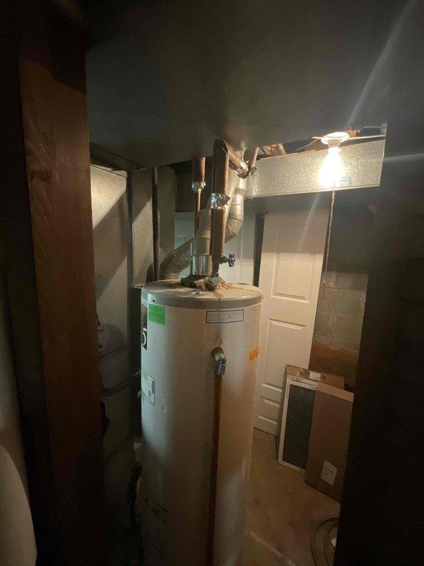Conducted estimate for standard hot water tank replacement in residential utility room. Assessed existing 10-year-old natural draft water heater currently in working condition with tight space constraints. Documented unit specifications, venting configuration, and mechanical connections including copper supply lines and flexible metal ductwork to provide accurate replacement recommendations.