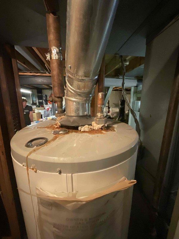 Conducted estimate for standard hot water tank replacement in residential utility room. Assessed existing 10-year-old natural draft water heater currently in working condition with tight space constraints. Documented unit specifications, venting configuration, and mechanical connections including copper supply lines and flexible metal ductwork to provide accurate replacement recommendations.